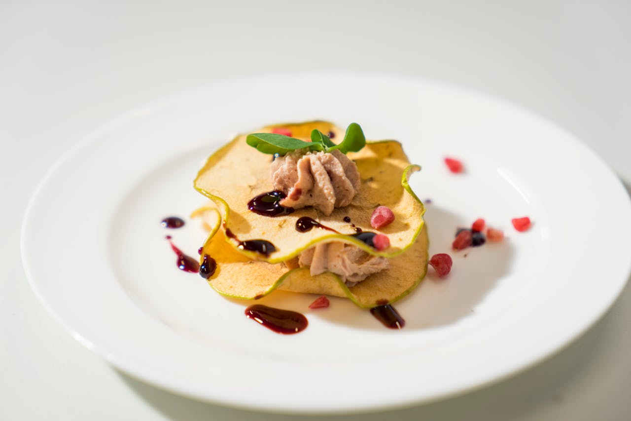 A stylishly presented dessert on a white plate, adorned with fresh garnishes and a drizzle of sauce.